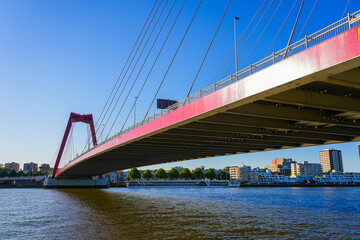 View of the underside of the road deck of the Willemsbrug suspension bridge in Rotterdam, crossing the Nieuwe Maas river in the Netherlands - Red steel road bridge with two towers