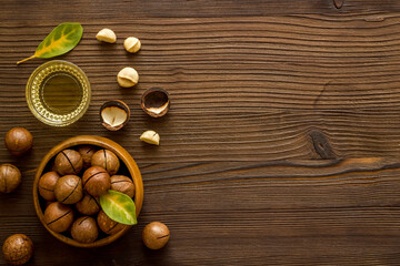 Fototapeta na wymiar Bowl of of macadamia nuts oil with raw nuts. Natural oil for cosmetic or cooking