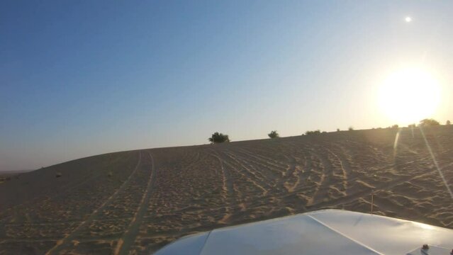 4K POV of a vehicle dune bashing on the sand dunes of the Thar desert at Jaisalmer in Rajasthan, India. Car moves on the desert during the day. Extreme adventure in the desert background.