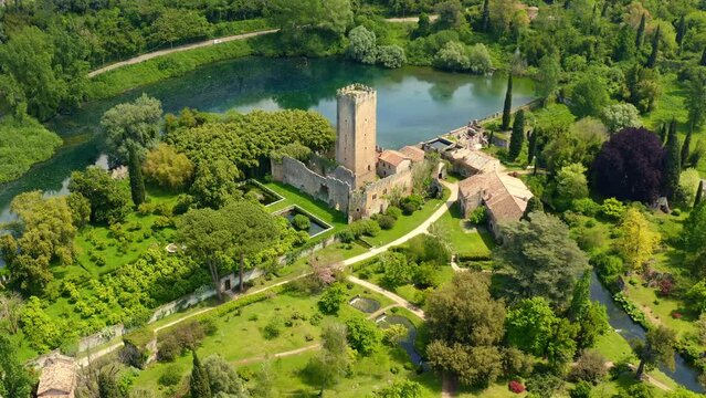 Aerial view of the ruins of the castle and tower located in the Garden of Ninfa, near Latina, Italy. The park is an Italian natural monument and contains a lake and a river. It is empty.