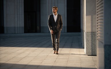 Elegant handsome man in classic suit standing near the office building.