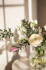 Bouquet of flowers in a glass vase on a light background. Eucalyptus and ranunculus.
