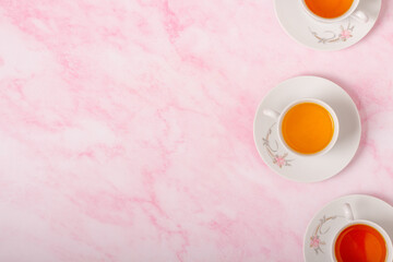 Three cups of tea on pink background. Top view. Copy space.