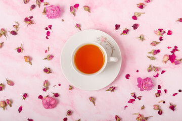Cup of tea on pink background with flowers. Top view. closeup