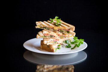 fried toasts stuffed with sausage, cheese and greens inside, on black background.