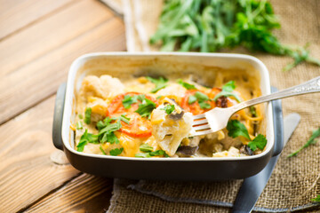 cauliflower baked with chicken fillet and mushrooms under cheese in a ceramic form
