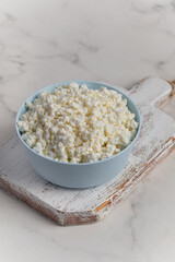 Cottage cheese in a bowl on a light background. Marble background.