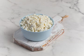 Cottage cheese in a bowl on a light background. Marble background.