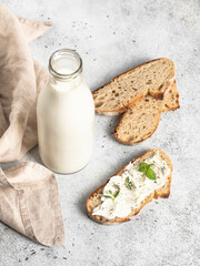 A bottle of milk, sliced ​​bread, bread smeared with cream cheese.