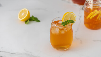 A glass with a summer cooling drink. Iced tea with lemon and mint.