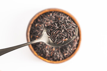 Raw black rice in the bowl on white background