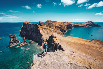 Athletic woman enjoys the view on rocky cliff from a steep cliff. São Lourenço, Madeira Island, Portugal, Europe.