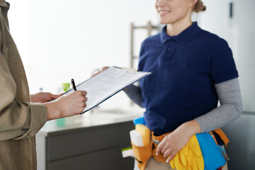 Close-up of housewife signing a contract with cleaning service worker to hire professional to do housework - obrazy, fototapety, plakaty