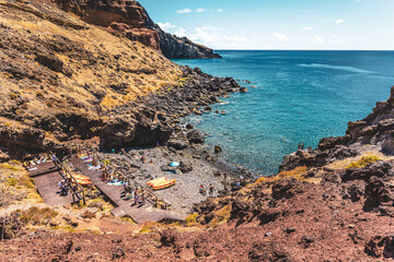 Tourists relax on beautiful stone beach with very clear water. São Lourenço, Madeira Island, Portugal, Europe.