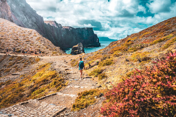 Athletic woman walking on paved trail with picturesque view of rocky coast of Madeira Island. São Lourenço, Madeira Island, Portugal, Europe.