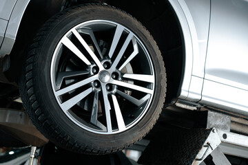 Car on a hoist in repair workshop with focus on the wheel
