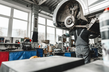 Auto mechanic repairs running gear of a car in car service