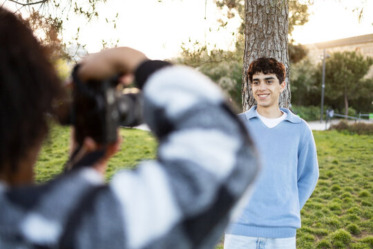 Unrecognizable photographer taking picture of happy young man