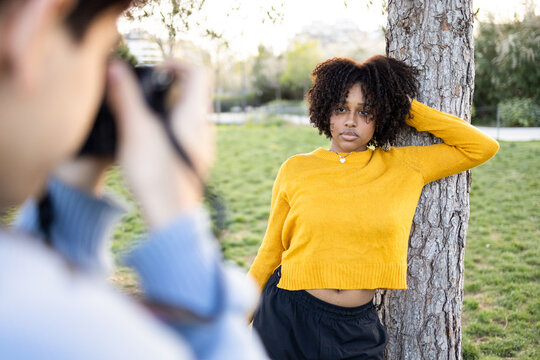 Black woman standing near tree for photo shooting