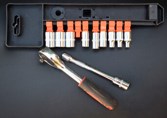 A set of socket heads with a ratchet on a black background, top view.