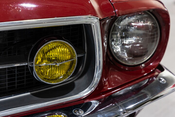 Close-up of the round headlamps of a red american classic car. Natural patine on the chrome details...