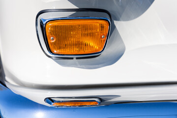 Close-up of the round turn indicator lights of a white classic car. Beautifully restored chrome...