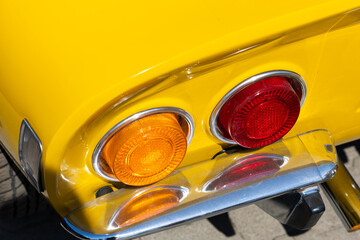 Close-up of the tale lights of yellow sport classic car. Beautifully restored details of a historic...