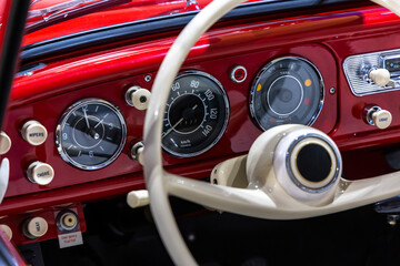 Dashboard of a stylish red classic car. The excellent restoration of the vehicle and whitesteering...