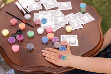 Kid's animator is creating a Shimmering sparkling glitter tattoo on a child's hand at a birthday party