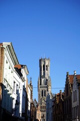 Blick durch die Altstadt auf den Turm des Belfried oder Belfort vor blauem Himmel im Sonnenschein...