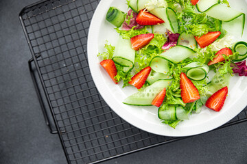 salad cucumber, strawberry, lettuce healthy meal food snack on the table copy space food background rustic top view keto or paleo diet veggie vegan or vegetarian food