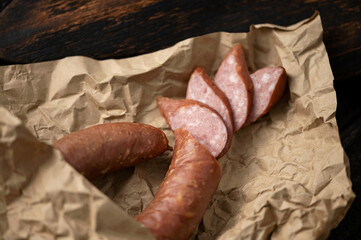 Half-smoked sausage ring. The sausage is cut into circles in wrapping paper on wooden board. Krakow...