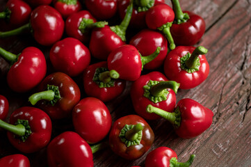 Red hot Cherry pepper. Lot of ripe peppers on wooden surface. Pepper harvest. Bright spices. Spicy food. North American pepper. Wooden background. Close-up. Soft focus. Top view. 