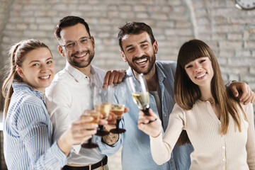 Group of happy business people toasting with wine at office party and looking at camera.