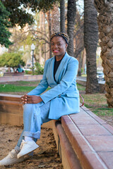 Obraz premium Black business woman smiles and looks at the camera while she is sitting in a park of a city
