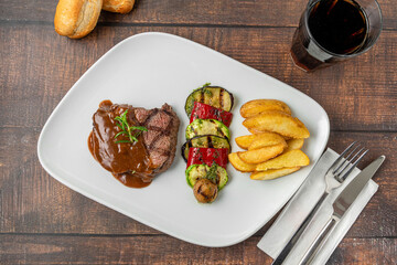Grilled beef tenderloin with Demi glace sauce with grilled vegetables on a white porcelain plate