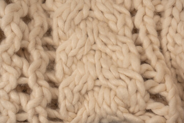 A fragment of beige knitted fabric, knitted from white sheep wool.
