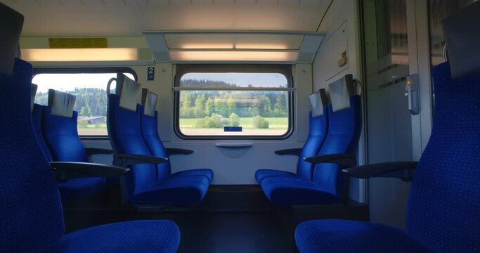 Passenger train ride with empty seats. Rolling green hills out the large windows, real time, cloudy day, Swiss public transport, no people