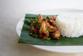 Thai street food restaurant menu: Stir fried crispy pork belly with Thai Jasmine Rice on Plates served with banana leaves in Thai style.