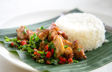 Thai street food restaurant menu: Stir fried crispy pork belly with Thai Jasmine Rice on Plates served with banana leaves in Thai style.