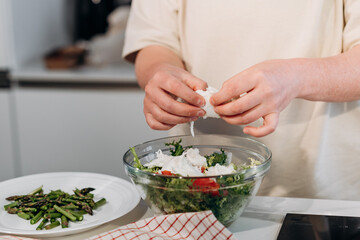 a woman prepares a healthy diet vegetable salad with tomatoes, mozzarella cheese, green salad, olive oil and balsamic