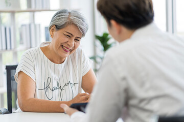 Obraz premium Asian seniors who are healthy, in a good mood, smiling, talking with financial or life insurance staff to take care of life after retirement...