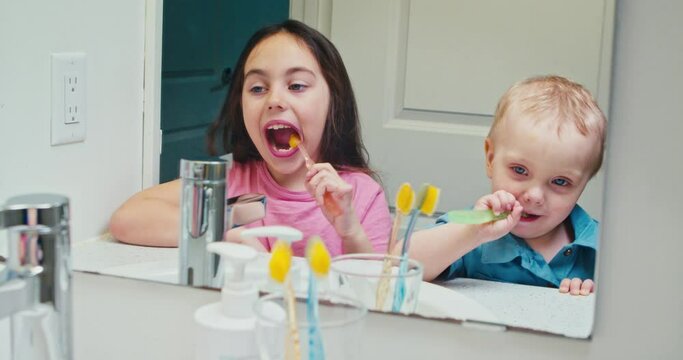 Cheerful brother and sister children brush their teeth in the morning and evening in the bathroom looking in the mirror. Children take care of their teeth from childhood, dental care. 