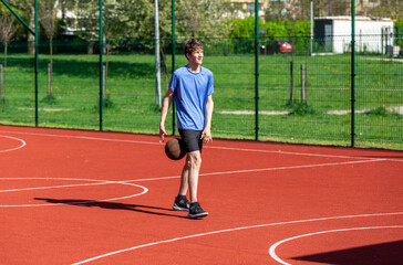 Obraz premium Boy playing basketball on court.Teenager running in the stadium. Sports, hobby, active lifestyle for boys 