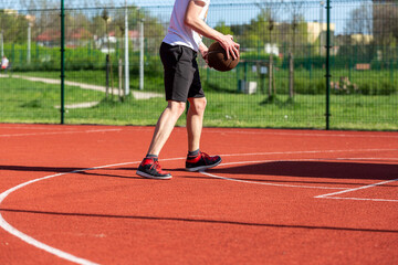 Obraz premium Boy playing basketball on court. Teenager running on the stadium. Sports, hobby, active lifestyle for boys 
