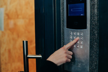 Woman hand press buttons on video intercom at entrance of apartment building in the night