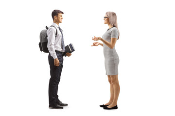 Full length profile shot of a young woman talking to a male teenage student in a school uniform