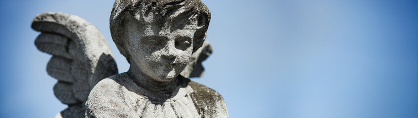 Ancient stone statue of guardian angel with wings. Copy space.