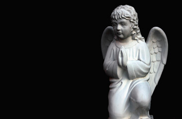 Fototapeta na wymiar Black and white image of little praying angel against dark background. Copy space.