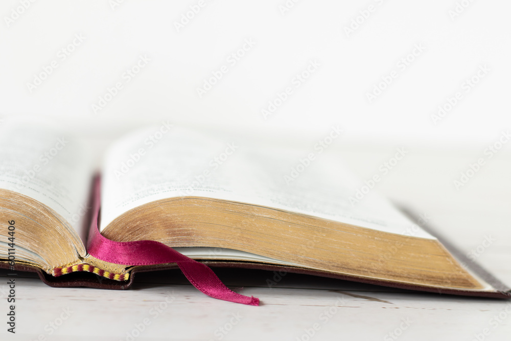 Wall mural closeup of open holy bible book with gold pages isolated on wooden table with white background. copy - Wall murals